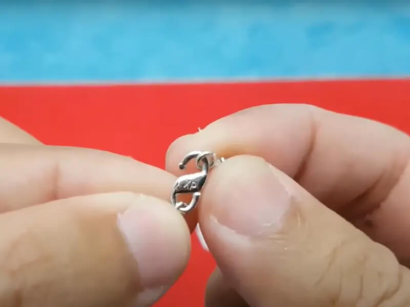 حکاکی دقیق XP روی قفل نقره‌ای یک زنجیر ژوپینگ، به‌وضوح قابل تشخیص در دست است